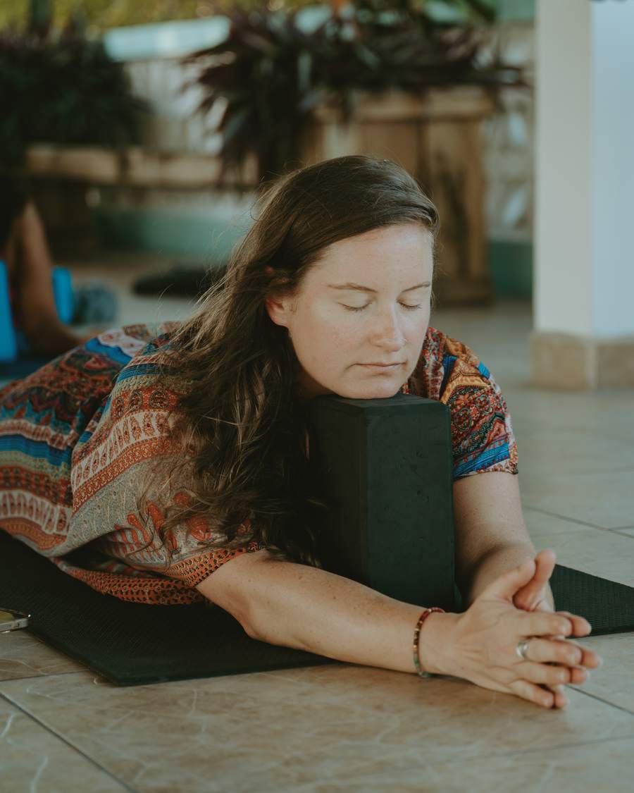 Megan resting forward over a yoga block, eyes closed, in a yin pose